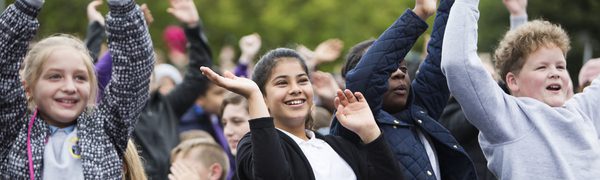 School children at the schools concert outside, smiling and dancing
