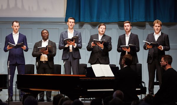 6 man stand on stage singing