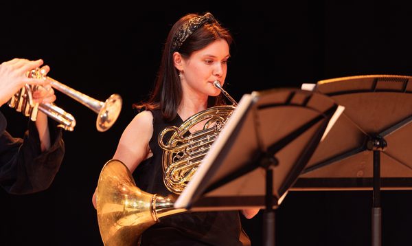 a young woman plays the french horn