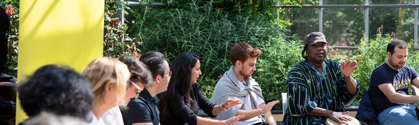 a group of people sit together playing the djembe