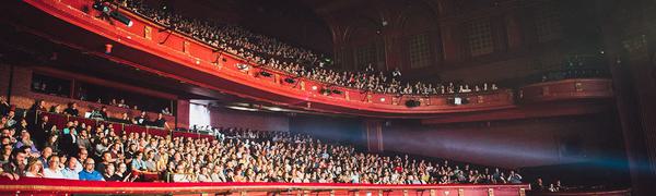 View of audience watching a show with light coming from the stage