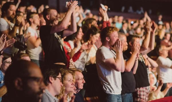 Crowd at a concert standing, cheering and clapping