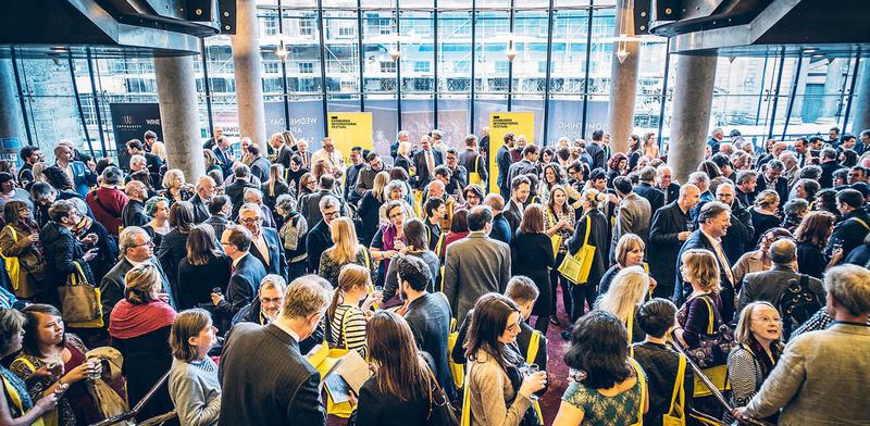 Looking down on a group of people in a theatre lobby. Holding Yellow EIF bags