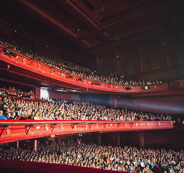 View of audience watching a show with light coming from the stage