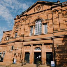 The red stone exterior of Church Hill Theatre with the sun shining on it