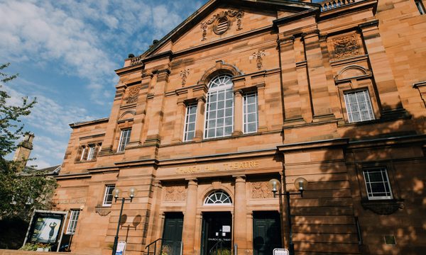 The red stone exterior of Church Hill Theatre with the sun shining on it
