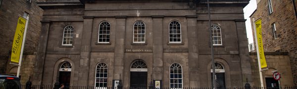 The brownstone exterior of Queen's Hall, with yellow Edinburgh International Festival banners either side