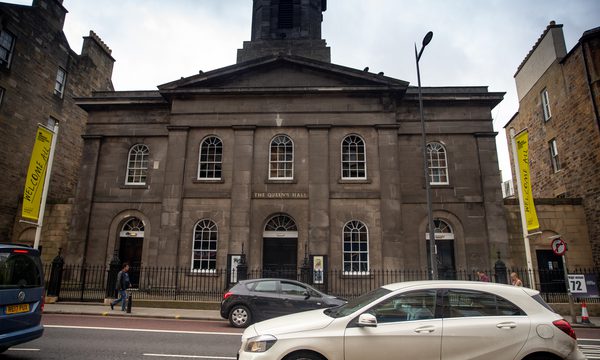 The brownstone exterior of Queen's Hall, with yellow Edinburgh International Festival banners either side