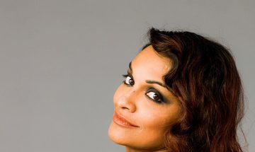 The singer pictured with her back to the camera, looking back over her left shoulder to smile at the camera.
