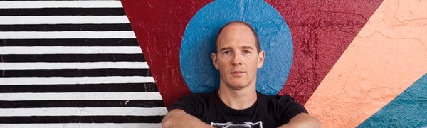 Caribou's Sam Shepherd since in front of a colourful mural