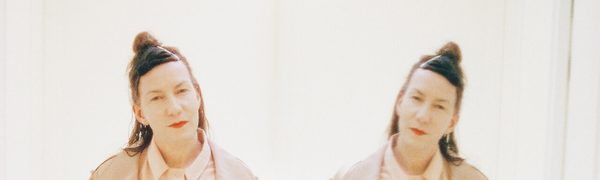 Twin mirror images of Kathryn Joseph, tilting her head and looking directly into the camera.