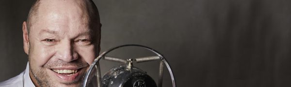 Thomas Quasthoff smiles behind an old-fashioned microphone