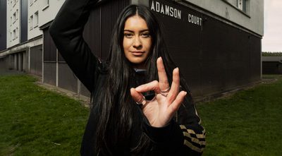 A young woman poses in front of a tower block