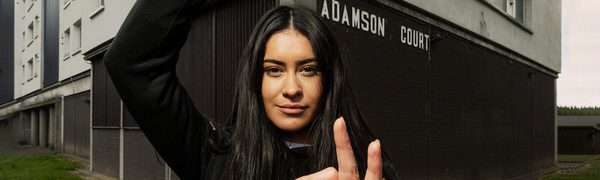A young woman poses in front of a tower block