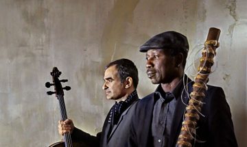 The two musicians pose with their instruments, gazing out to the left of the camera.