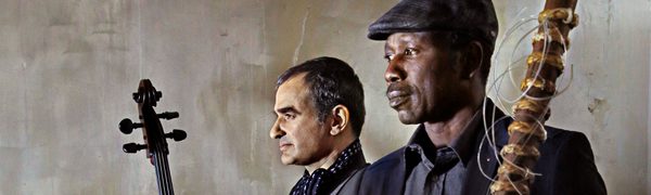 The two musicians pose with their instruments, gazing out to the left of the camera.