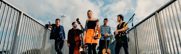 The Breabach members pose on a bridge with their instruments: fiddle, cello, bagpipes, guitar, and whistle