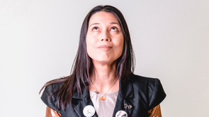 Head shot of Francesca Beard wearing a black and gold metallic top with badges