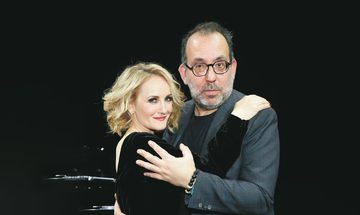 Katharine Mehrling and Barrie Kosky hold each other in a dancing pose and smile at the camera.
