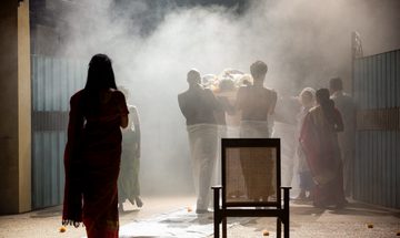 People are seen in silhouette carrying out a body on a stretcher over their shoulders