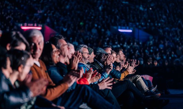 A group of people sit in the stands of Murrayfield stadium smiling and clapping