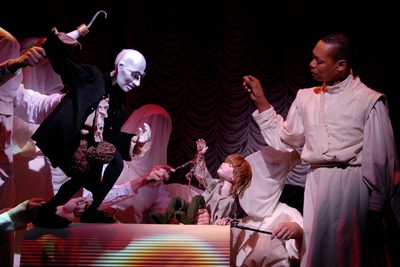 A puppet of a man with a hook towers over a puppet of a small boy