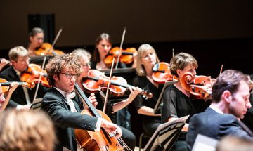 Musicians dressed in black suits and evening dresses playing cellos and violas