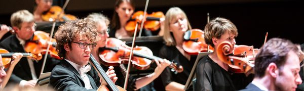Musicians dressed in black suits and evening dresses playing cellos and violas