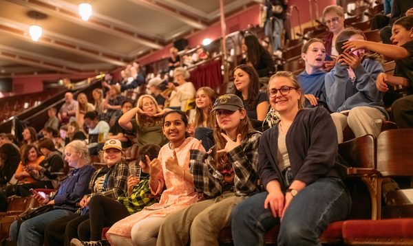 People sit in seats at the Festival Theate, waiting for a show to begin. They are smiling