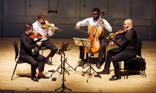 Four string musicians passionately play their instruments.
