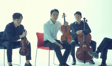 The quartet pictured casually dressed, sitting in relaxed positions on chairs holding their musical instruments.