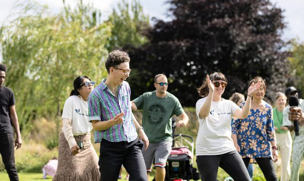 People dance in a park, they are smiling and laughing