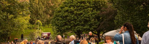 A group of people enjoying music in Princes Street Gardens with the castle in the background