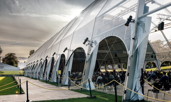 An image showing a very long gazebo with audience members seated inside