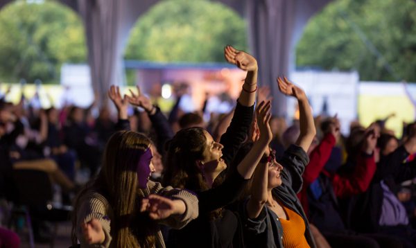 Audience members wave their arms in the air
