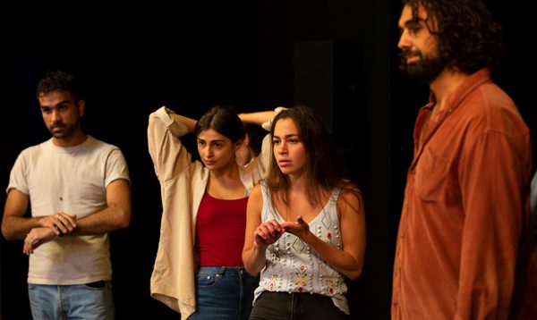 Two young women and two young men stand in casual poses, looking into the distance