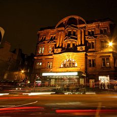 Outside of Edinburgh's Kings' Theatre light up at night with lights of cars passing by