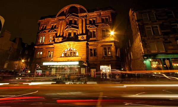 Outside of Edinburgh's Kings' Theatre light up at night with lights of cars passing by