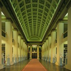 The interior of the Playfair Library, a neo-classical building with a long red carpet and painted ceiling, columns and statue busts