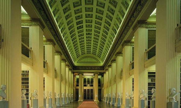 The interior of the Playfair Library, a neo-classical building with a long red carpet and painted ceiling, columns and statue busts