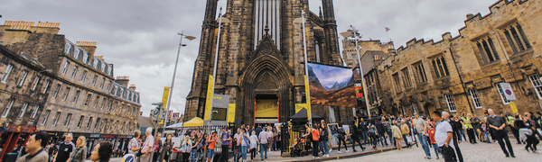 The front of The Hub, a neo-gothic church at the top of the Royal Mile, with many people walking in front of it