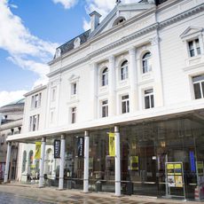 The white exterior of a theatre with yellow Edinburgh International Festival banners on the pillars outside