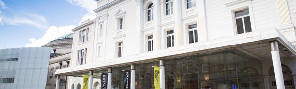The white exterior of a theatre with yellow Edinburgh International Festival banners on the pillars outside