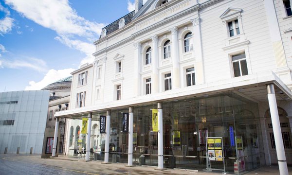 The white exterior of a theatre with yellow Edinburgh International Festival banners on the pillars outside