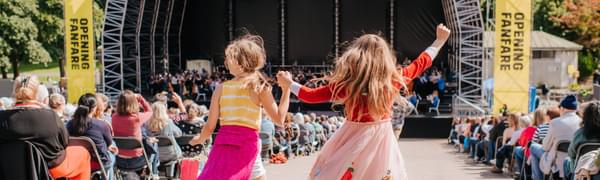 Two young girls stand dancing overlooking a big stage in Princes Street Gardens
