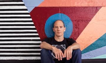 Caribou's Sam Shepherd since in front of a colourful mural