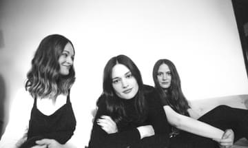 Black and white photo of the three sisters of The Staves, posing on a sofa