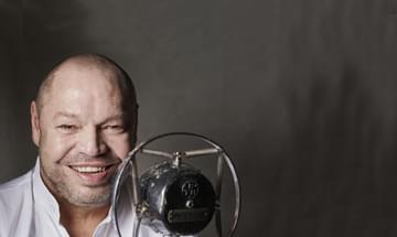 Thomas Quasthoff smiles behind an old-fashioned microphone