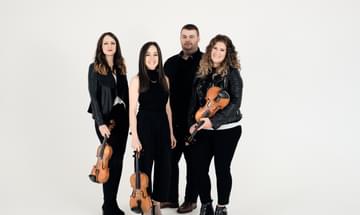 The four members of Fara pose together; three women with fiddles and one man, all dressed in black.