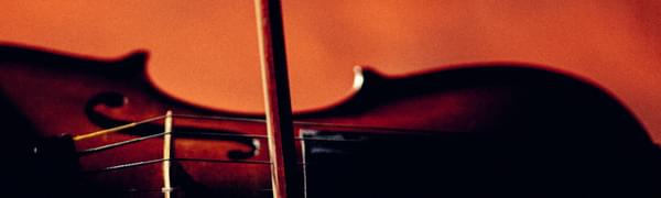A close-up shot of a violin being played against a deep orange background